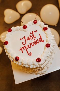 a heart shaped birthday cake with the words just married written on it and cherries