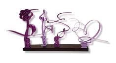 the word love is made out of purple ribbon and plastic letters on a black stand