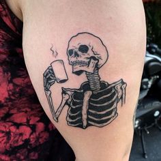 a woman with a tattoo on her arm has a skeleton holding a cup in it's hand