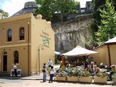 people are standing in front of a building with many plants on the outside and an awning over it