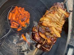 a bbq with carrots and meat on it next to a bowl of broccoli