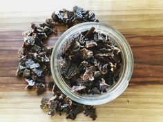 a glass bowl filled with raisins sitting on top of a wooden table next to a pile of raisins