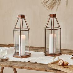 two glass lanterns sitting on top of a wooden table next to shells and seashells