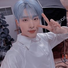 a man with blue hair making the peace sign