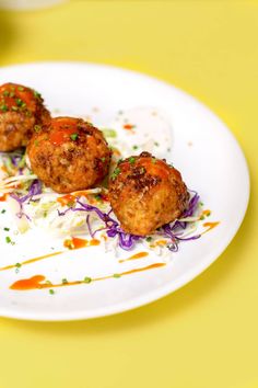 three meatballs on a white plate with sauce and sprinkles around them