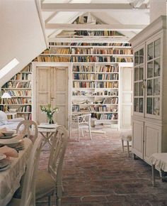 a room filled with lots of books on top of a book shelf next to a dining table