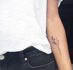 a woman's left arm with a small flower tattoo on the right side of her upper arm