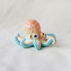 an octopus figurine sitting on top of a white sheet with blue and yellow dots