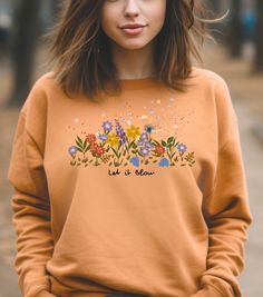 Feel the breeze with this colorful sweatshirt featuring flying petals and blooming flowers. The inscription 'Let it blow' adds a touch of whimsy. Perfect for those who love nature and vibrant designs, this sweatshirt is ideal for casual wear or cozy nights in during the fall and winter seasons. ABOUT THE PRODUCT ➤ Gildan 18000 sweatshirt made with a medium-heavy fabric blend of 50% cotton and 50% polyester (8.0 oz/yd² (271.25 g/m feels cozy and is the perfect choice for those colder months ➤ Made using 100% ethically grown US cotton ➤ Say goodbye to itchiness thanks to the gray, pearlized tear-away label SIZE ➤ Take a look at the photos to see a specific sizing chart for this sweatshirt ➤ Please note that these sweatshirts are unisex size meaning they are not women's fitted shirts. If you' Garden Clothing, Colorful Sweatshirt, Fitted Shirts, Gardening Outfit, Love Nature, Gifts For Nature Lovers, Blooming Flowers, Botanical Garden, Look Plus