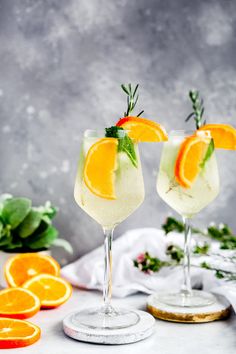 two glasses filled with lemonade and garnished with orange slices on a table