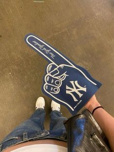 someone is holding up a new york yankees baseball bat shaped towel on the floor in front of their feet