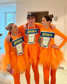 three people in orange tutus and aprons are posing for the camera with their arms around each other