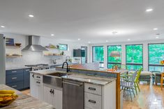 a kitchen with an island, sink, and stove top oven in front of large windows