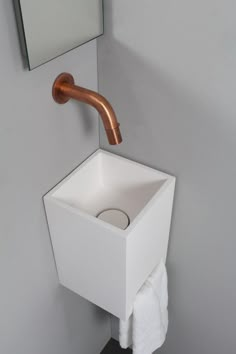 a white sink with a copper faucet and mirror above it in a bathroom