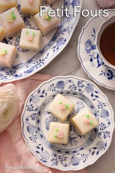 small pieces of cake sitting on top of a blue and white plate next to a cup of tea