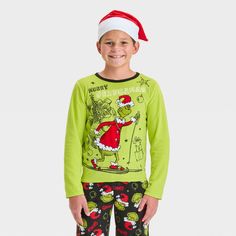 Surprise your kid during Christmas with The Grinch 2-Piece Cozy Pajama Set and Santa Hat. This two-piece pajama set includes a green sleep shirt, a pair of black pajama pants and a Santa hat for a festive look. The top showcases a print of the Grinch wearing a Santa outfit on skis with "Merry Grinchmas" text, while the bottom showcases allover Grinch faces wearing Santa hats and the name "Grinch" for holiday fun. Grinch Faces, Black Pajama Pants, Grinch Pajamas, The Grinch Christmas, Black Pajamas, Merry Grinchmas, Santa Outfit, Cozy Pajamas, Santa Hats