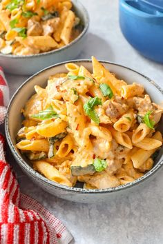 two bowls filled with pasta and vegetables on top of a table