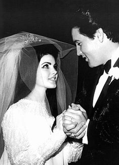 a black and white photo of a bride and groom holding each other's hands