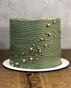 a green frosted cake sitting on top of a wooden table next to a white plate