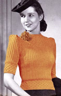 a woman in an orange sweater and black skirt with a hat on top of her head