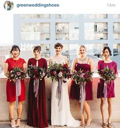 a group of women standing next to each other wearing dresses and holding bouquets in their hands