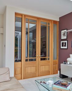 a living room with glass coffee table and wooden doors in the center, surrounded by pictures on the wall