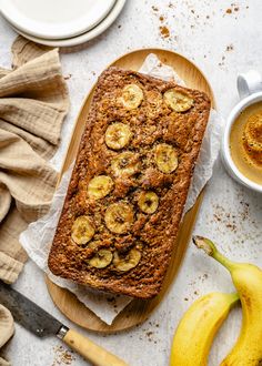 a loaf of banana bread sitting on top of a cutting board next to some bananas