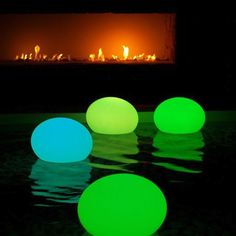 three glowing balls sitting in front of an open fire place with the reflection of it on the water