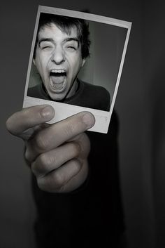 a man holding up a polaroid with his mouth open