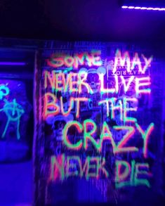 some graffiti on a wall in a dark room with neon colors and words written all over it