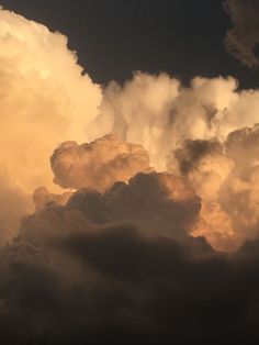 an airplane is flying through the clouds at sunset