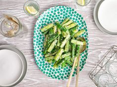 a plate filled with asparagus on top of a table next to glasses and plates