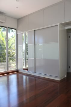 an empty room with sliding glass doors and hard wood flooring on the side wall