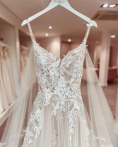 a wedding dress hanging on a hanger in a bridal gown shop with white flowers