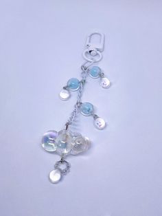 a white necklace with blue and clear beads on it's end, hanging from a silver chain