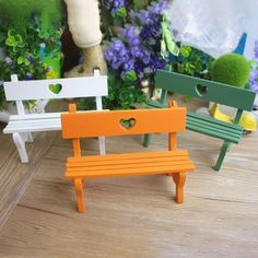 three miniature benches sitting next to each other on a wooden floor with flowers in the background