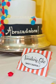 a table topped with a cake covered in frosting next to a sign that says vanishing cake