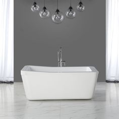 a white bath tub sitting next to a window with hanging lights on it's side