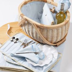 a basket filled with silverware next to napkins and wine bottles on top of a wooden tray