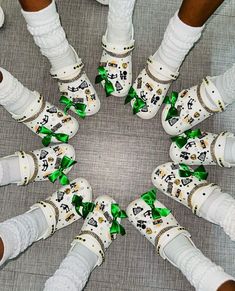 several pairs of white shoes with green bows are arranged in a circle