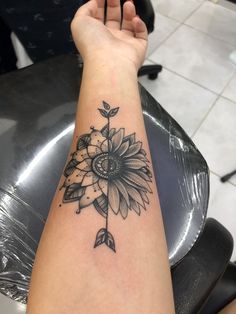 a woman's arm with a tattoo that has a sunflower and leaves on it