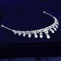 Adorned with intricately faceted clear cubic zirconia that work their way across the band in a swirly pattern and capturing the light from every angle with a perfectly translucent appeal, this delicate tiara can complete the most sophisticated of bridal looks. Cast in lightweight alloy and rhodium plated for a flawless finish, the headband measures 1.25" at the highest point (approx. 3cm) and 5.5" across (approx. 14cm). Two small loops at each end make it easy to attach to your hair with bobby p Wedding Jewelry With Diamond Crown Design, Wedding Jewelry With Crown Design, Wedding Diamond Crown Design Jewelry, Wedding Diamond Crown Jewelry, Teardrop Crown Jewelry With Rhinestones For Wedding, Diamond Crown Jewelry For Wedding, Silver Wedding Crown With Pinched Shape, Adjustable Silver Wedding Crown, Silver Crown Headpiece For Wedding