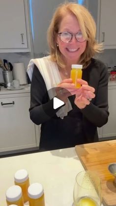 a woman holding up a cell phone in front of some bottles and glasses on a counter