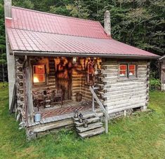 an old log cabin with a red roof and steps leading up to the front door