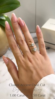 a woman's hand with two diamond rings on her left and the other hand holding an engagement ring