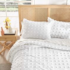 a bed with white polka dot sheets and pillows