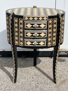 a black and white table with drawers on it's sides, in front of a wall