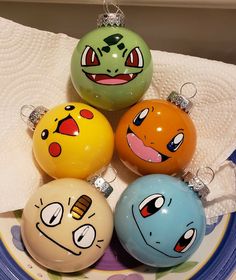 four different colored balls with faces on them sitting on a blue and white plate next to a towel