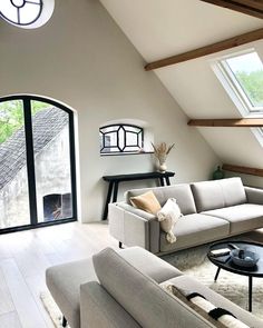 a living room with two couches, a coffee table and an arched window in the ceiling