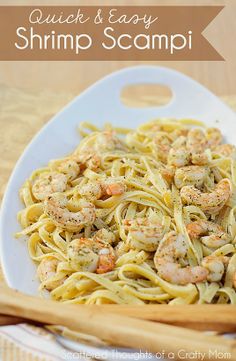 shrimp scampi pasta on a white plate with wooden utensils next to it